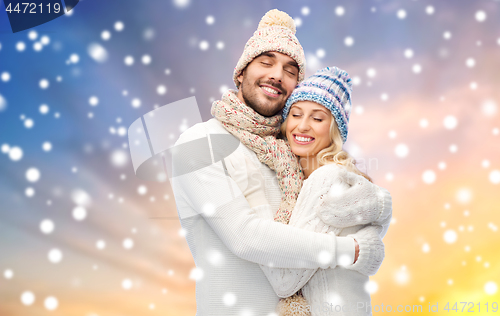 Image of happy couple in winter clothes hugging over snow