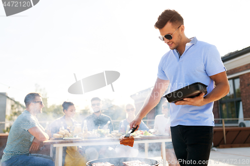 Image of man cooking meat on bbq at rooftop party