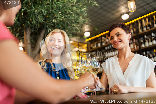 Image of happy women drinking wine at bar or restaurant