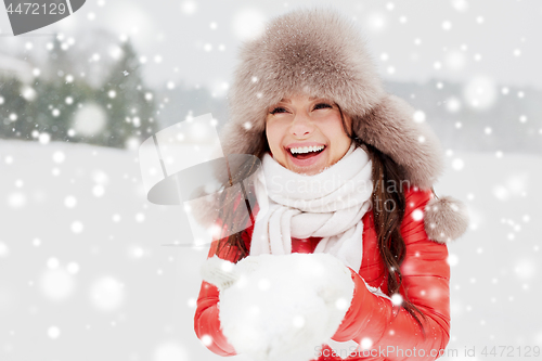 Image of happy woman with snow in winter fur hat outdoors