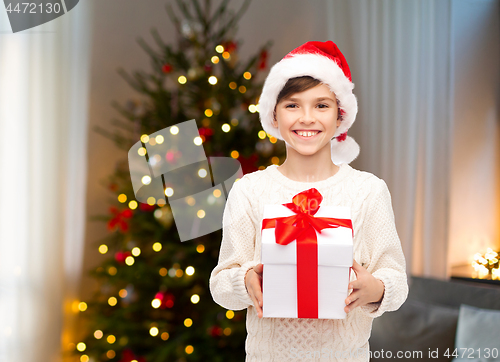 Image of happy boy in santa hat with gift box on christmas