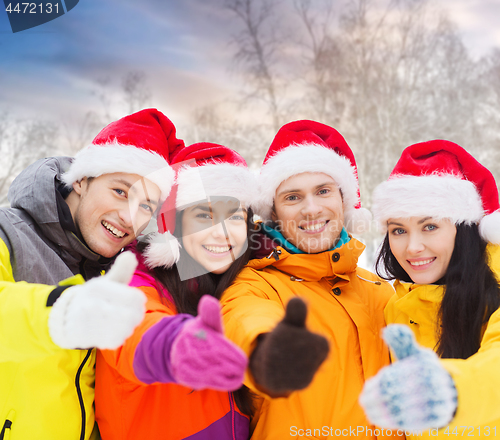 Image of friends in santa hats showing thumbs up outdoors