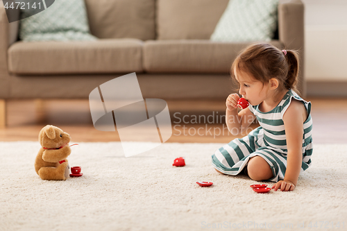 Image of little girl playing with toy tea set at home