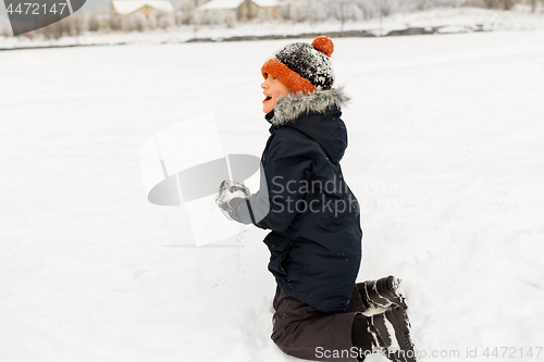 Image of happy little boy playing with snow in winter