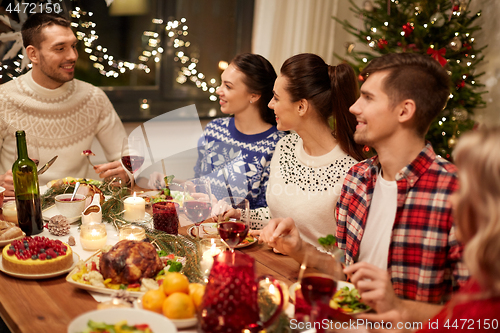 Image of happy friends having christmas dinner at home