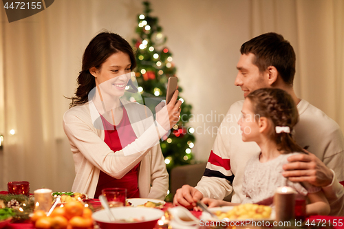 Image of happy family taking picture at christmas dinner