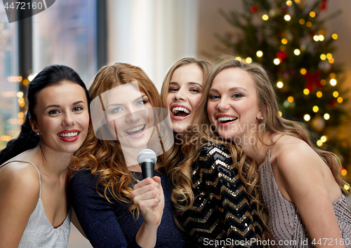 Image of happy young women with microphone singing karaoke