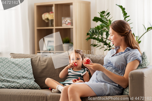 Image of pregnant mother and daughter playing tea party