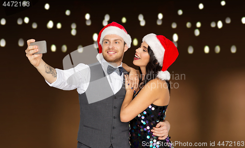 Image of couple in santa hats taking selfie at christmas