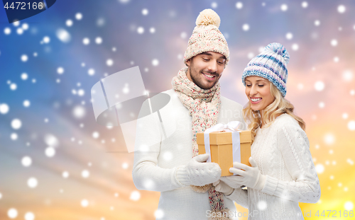 Image of smiling couple in winter clothes with gift box