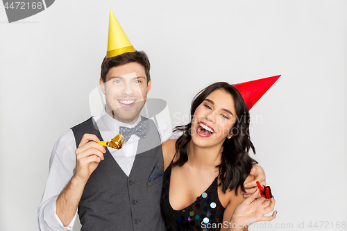 Image of happy couple with party blowers having fun