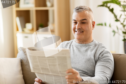 Image of man reading newspaper at home