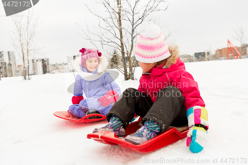 Image of happy little girls on sleds outdoors in winter