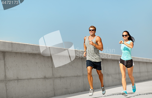 Image of couple in sports clothes running outdoors