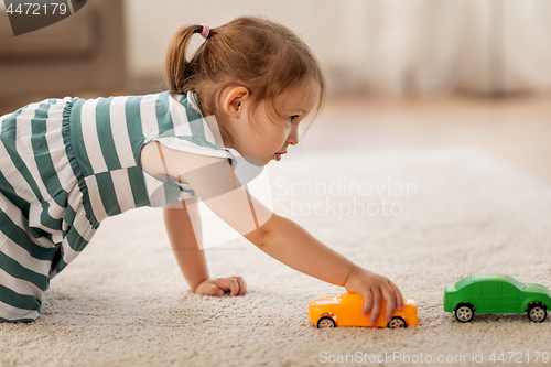 Image of happy baby girl playing with toy car at home