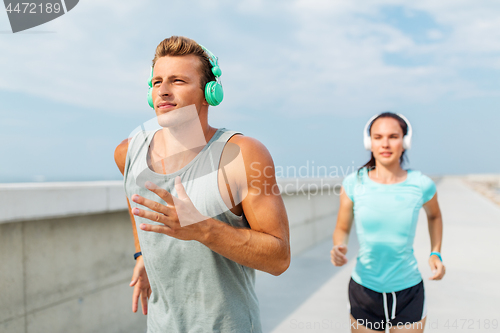 Image of couple with headphones running outdoors