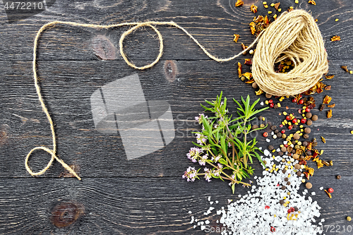 Image of Thyme leaves and flowers with twine on black board