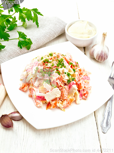 Image of Salad of surimi and tomatoes with mayonnaise on light wooden boa