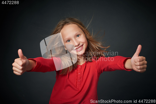 Image of Happy girl gesturing thumbs up hand sign