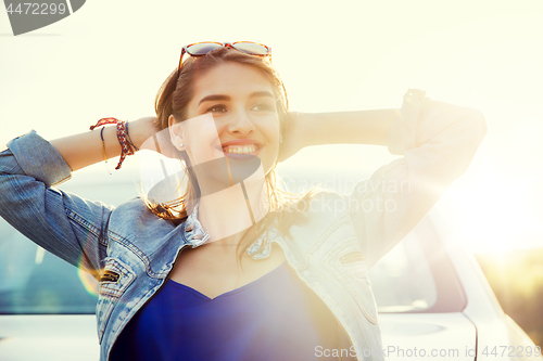 Image of happy teenage girl or young woman near car