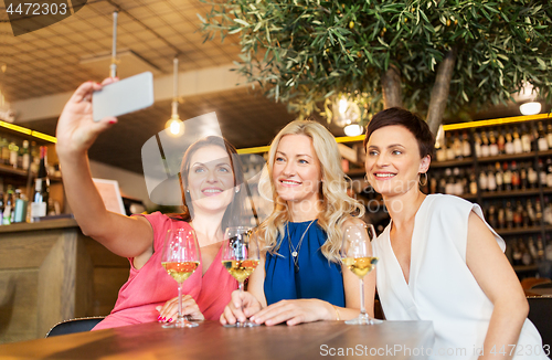 Image of women taking selfie by smartphone at wine bar
