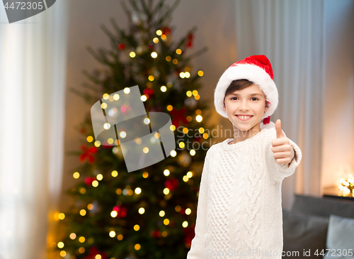 Image of happy boy in santa hat showing thumbs up