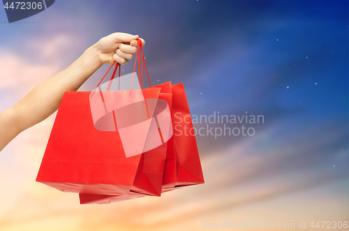 Image of close up of male hand holding red shopping bags