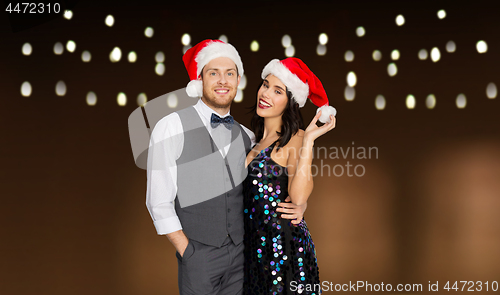Image of happy couple in santa hats at christmas party