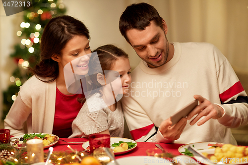 Image of family with smartphone having christmas dinner