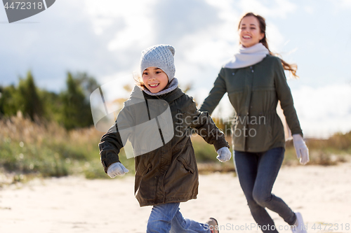 Image of happy family running along autumn beach