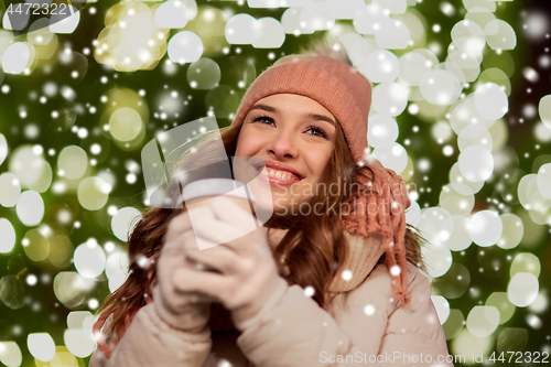 Image of happy woman with coffee over christmas lights