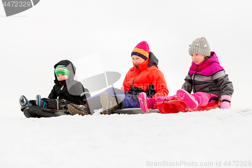 Image of happy little kids sliding on sleds in winter