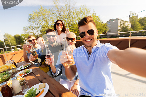 Image of happy friends taking selfie at rooftop party