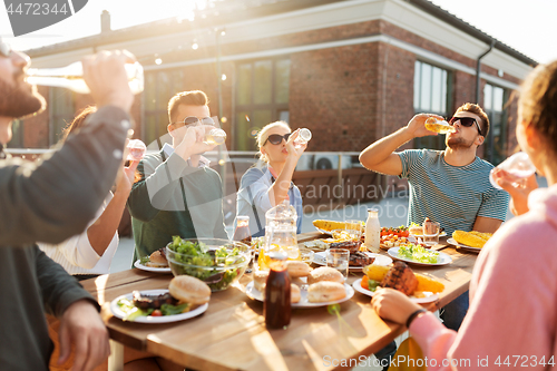 Image of happy friends with drinks or bbq party on rooftop