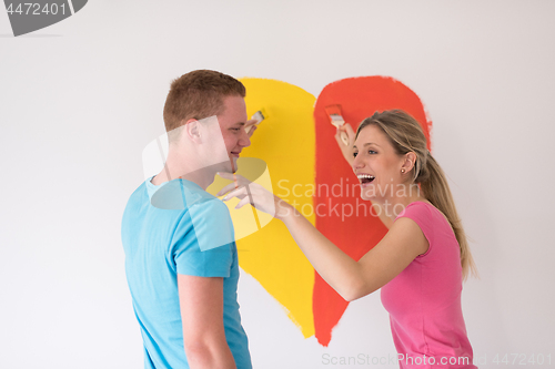 Image of couple are painting a heart on the wall