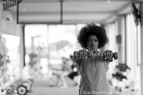 Image of woman working out in a crossfit gym with dumbbells