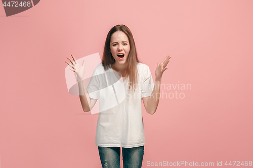 Image of Portrait of angry teen girl on a pink studio background