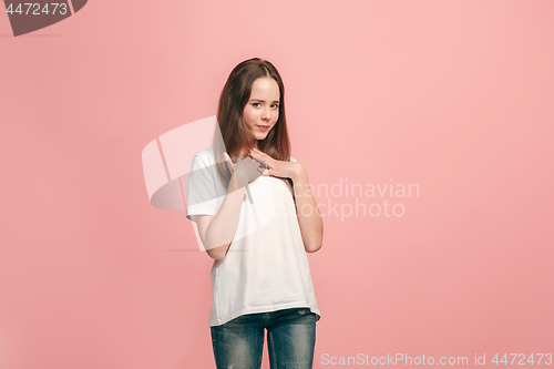 Image of The happy teen girl standing and smiling against pink background.