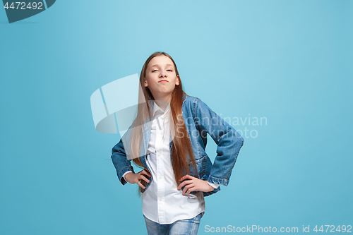 Image of The happy teen girl standing and smiling against blue background.