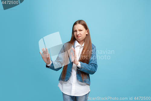 Image of Doubtful pensive teen girl rejecting something against blue background