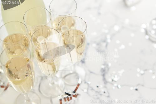 Image of Champagne glasses and bottle placed on white marble background