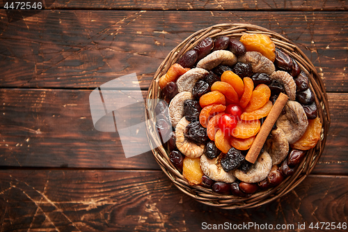 Image of Mix of dried fruits in a small wicker basket on wooden table