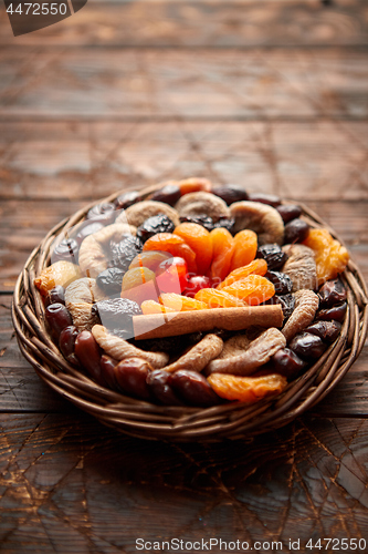 Image of Mix of dried fruits in a small wicker basket on wooden table
