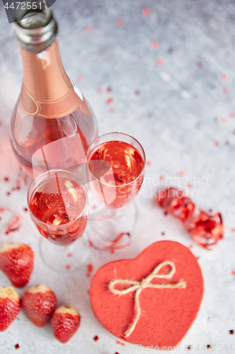 Image of Bottle of rose champagne, glasses with fresh strawberries and heart shaped gift