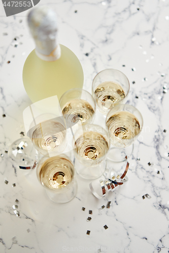 Image of Champagne glasses and bottle placed on white marble background