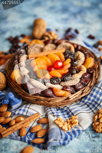 Image of Composition of dried fruits and nuts in small wicker bowl placed on stone table