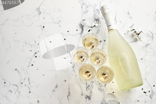 Image of Champagne glasses and bottle placed on white marble background