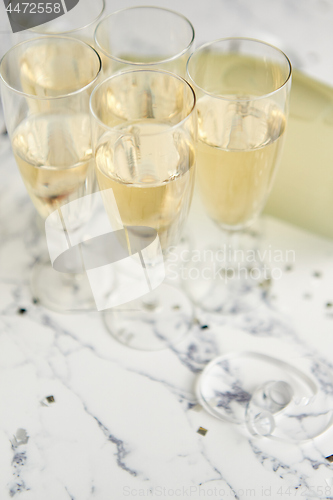 Image of Champagne glasses and bottle placed on white marble background