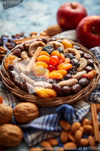 Image of Composition of dried fruits and nuts in small wicker bowl placed on stone table