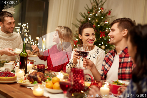 Image of happy friends having christmas dinner at home